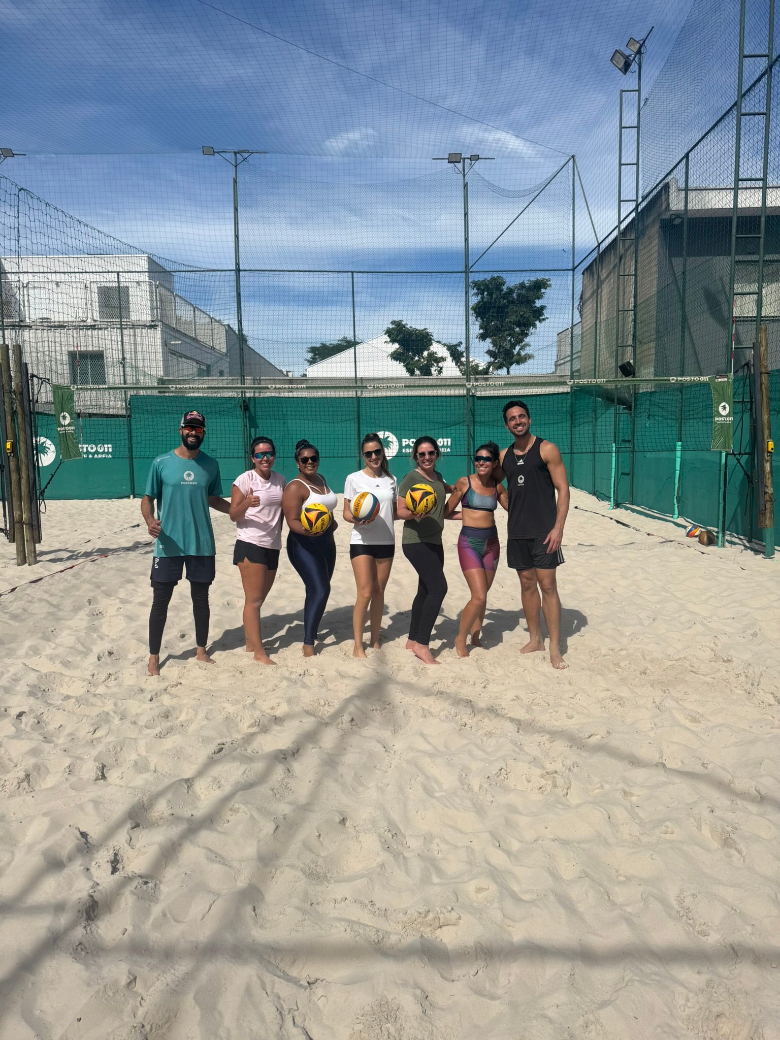 Professores e alunas reunidos na quadra após uma clínica de vôlei de praia
